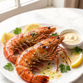 Two grilled tiger prawns plated with lemon and butter sauce